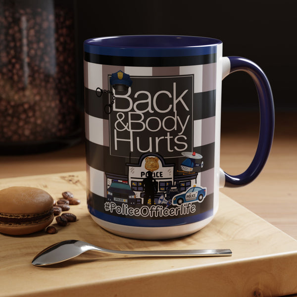 A mug with a graphic design featuring police officers and the text "Back & Body Hurts" on it, placed on a wooden surface next to a spoon.